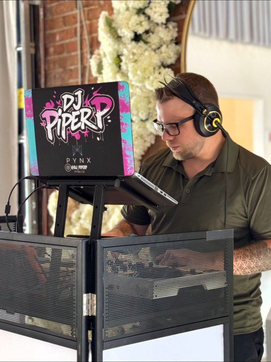 DJ Piper at the booth, headphones on, with the DJ Piper P laptop.